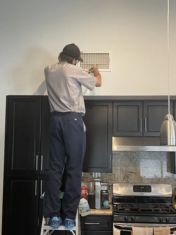 Technician inspecting an air vent during HVAC service in Quincy